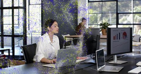Businesswoman working at dual-monitor workstation in modern open-plan office