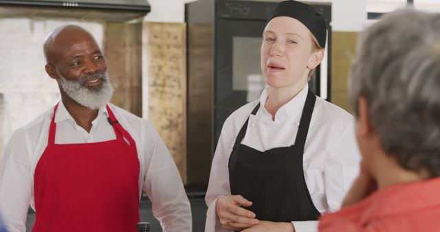 Group of chefs engaging in lively discussion in a commercial kitchen. This can be used in contexts related to professional kitchens, restaurant teams, culinary training, and hospitality industry promotional materials. Ideal for illustrating team collaboration, chef training programs, and professional culinary environments.