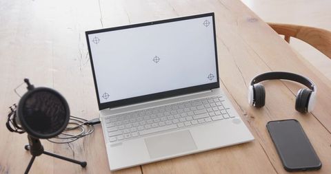 Minimalist home office recording setup featuring laptop microphone headphones for podcasting