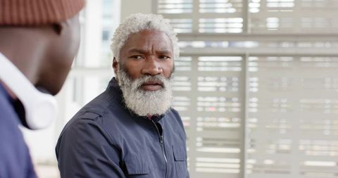 Mature african american man with white beard listening and speaking in modern waiting area