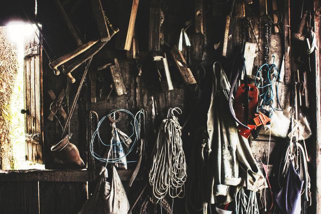 This image shows a rustic workshop's interior wall filled with hanging tools and ropes. It captures the essence of traditional craftsmanship and manual labor with its cluttered arrangement of equipment and materials. Ideal for use in content related to DIY projects, craftsmanship, traditional carpentry, and rustic decor aesthetics.