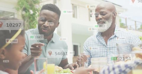 Intergenerational family sharing backyard meal with pointing son and digital map overlays