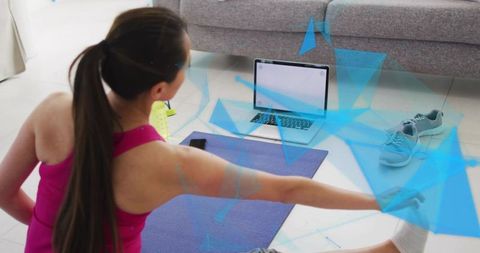 Korean woman stretching on yoga mat during home workout with laptop and sneakers