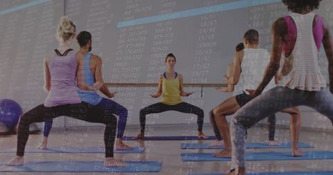 Trainer guiding barre plie squat in group fitness class with digital code overlay