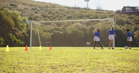 Girls practicing soccer on school field with goal setting