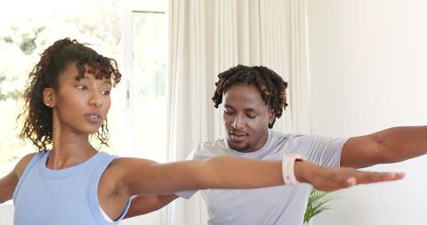 African american couple stretching together in bright home living room for fitness