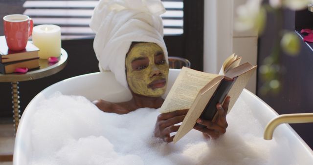 African american woman with towel and mask taking bath and reading book in bathroom - Download Free Stock Photos Pikwizard.com