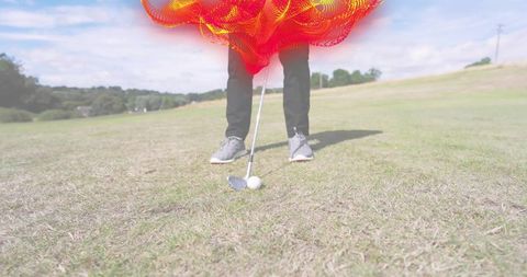 Male golfer standing ready to strike golf ball on sunlit fairway close-up with abstract red overlay
