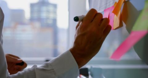 Executive Updating Sticky Notes in Modern Office