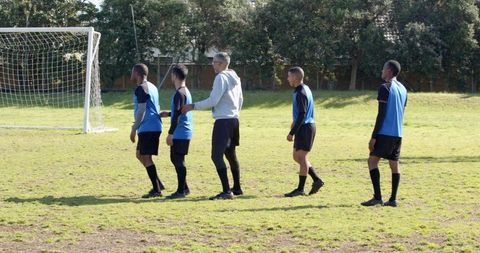 Diverse soccer team forming defensive wall in training session