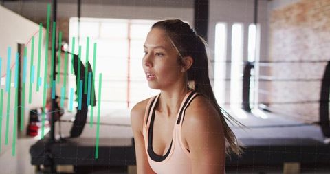 Young woman resting and breathing after boxing workout in urban gym with data overlay