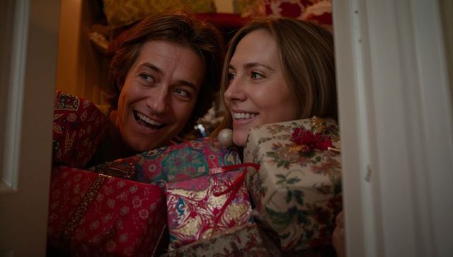 Two women laughing among holiday gift boxes