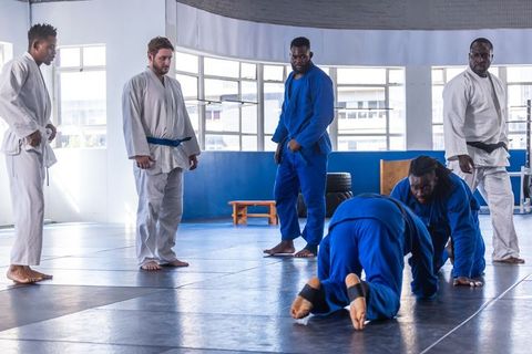 Martial Artists Practicing Moves in a Modern Dojo