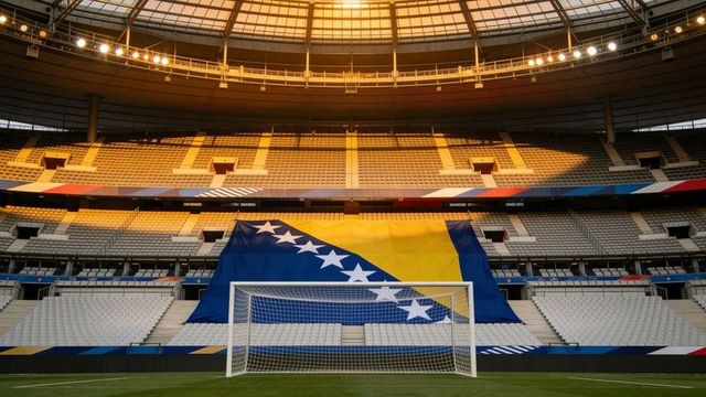 Giant bosnia and herzegovina flag draping stands at empty football stadium under dome