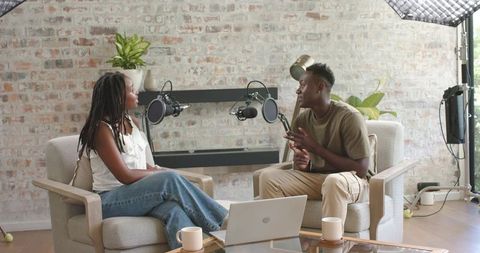 African american cohosts recording conversational podcast in cozy brick wall home studio