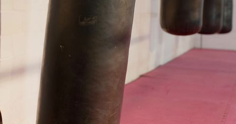 Heavy bag and focus pads on pink mats for martial arts and combat fitness training