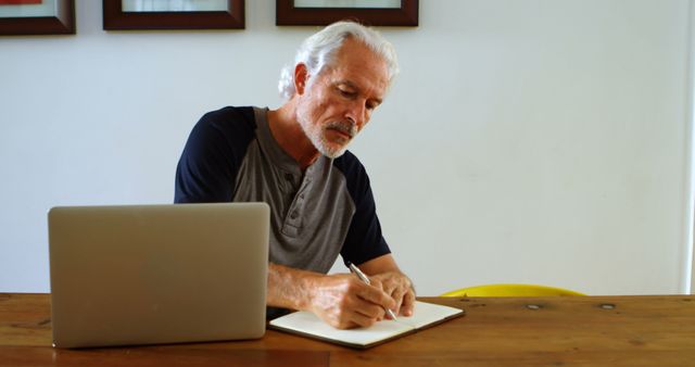 Senior Man Writing in Notebook near Laptop at Home - Download Free Stock Images Pikwizard.com