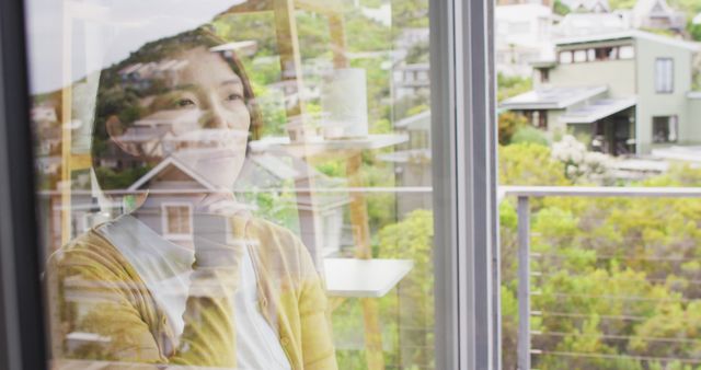 Asian woman touching her chin and thinking at window alone. Spending quality time at home.