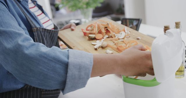 Person Disposing Vegetable Peelings into Compost Bin in Kitchen - Download Free Stock Images Pikwizard.com