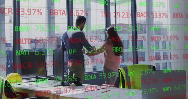 Shows two business professionals analyzing data in an office setting with a digital stock market projection overlay. Useful for illustrating financial analysis, teamwork, or modern business technology themes.