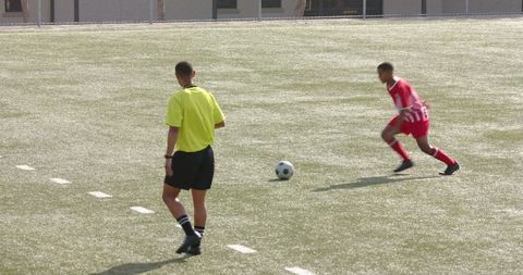 Focused Soccer Player Training with Referee Observing on Field