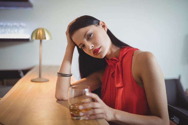 Portrait of tensed woman having a glass of whisky in restaurant