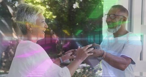 Mature couple holding hands laughing on porch with colorful light overlays and lens flare