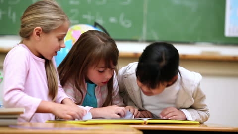 Children Intently Reading Book in Classroom Setting