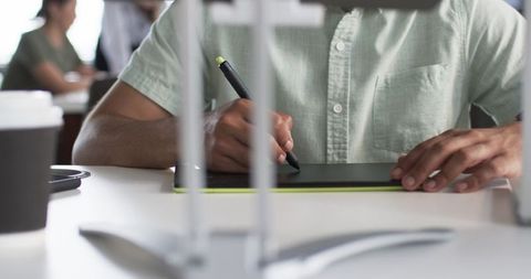 Close-up of hands drawing with stylus on tablet in creative workspace