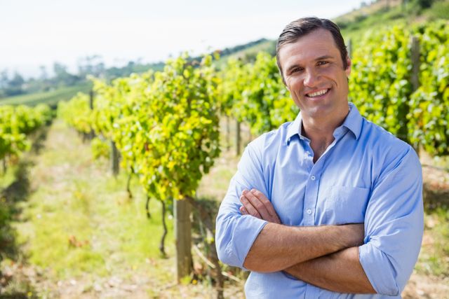 Portrait of smiling vintner standing with arms crossed in vineyard