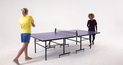 Dynamic women enjoying table tennis game in studio
