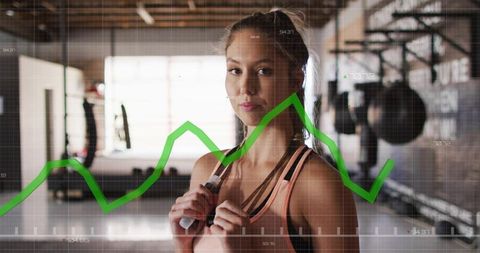 Woman holding jump rope displaying fitness analytics overlay in industrial gym