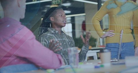 Young professional with dreadlocks speaking and gesturing during team brainstorming session