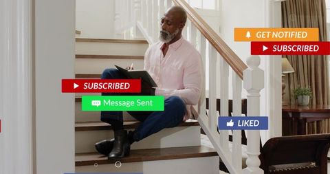 Writing man sitting on wooden stairs at home with tablet notebook and social notifications