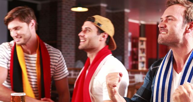 Excited handsome friends watching sports at bar