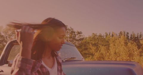 Woman checking car engine outdoors with sunset