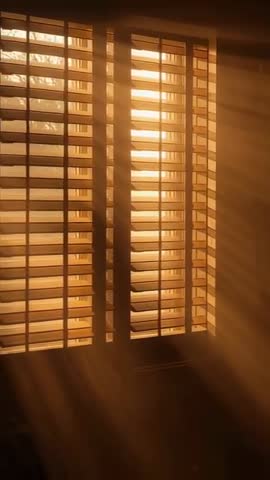 Sunlight Streaming Through Plantation Shutters Casting Warm Golden Beams Across Room