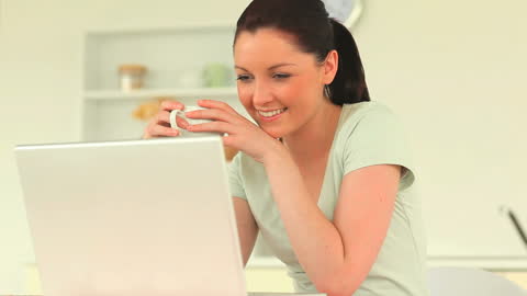 Smiling Woman Relaxing with Laptop in Modern Kitchen