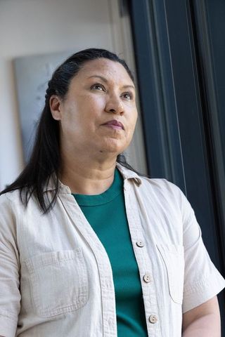 Contemplative african american woman standing by window, gazing upward in natural light