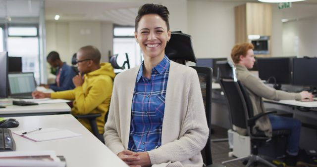Caucasian woman sitting at desk looking at camera and smiling at camera in office. business, teamwork and office workplace.