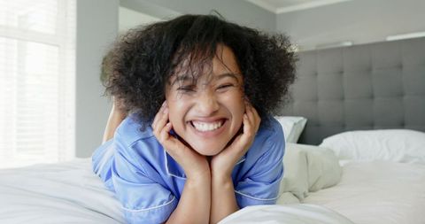 Joyful Woman Relaxing on Bed in Comfortable Pajamas