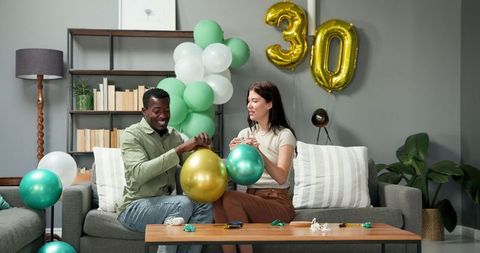 Multiracial couple preparing for birthday celebration with balloons