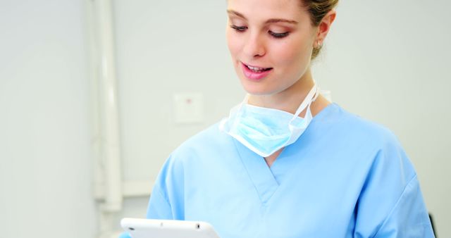 Healthcare professional in scrubs is using a tablet for clinical tasks such as accessing patient records, viewing treatment plans, or communicating with other medical staff. Ideal for content related to modern healthcare solutions, hospital technology, medical professionals at work, or telehealth services.