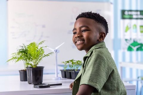 African american boy smiling and exploring plants and wind energy in classroom lab
