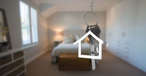 Hanging keys with house-shaped charm in cozy bedroom interior