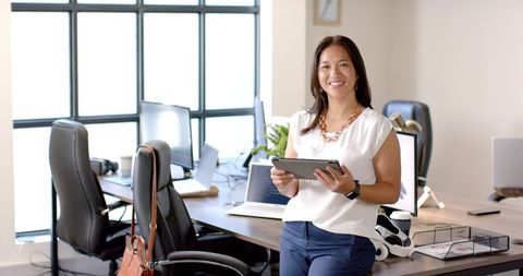 Smiling professional woman holding tablet in bright office