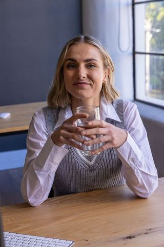 Woman in Professional Workspace Holding Glass