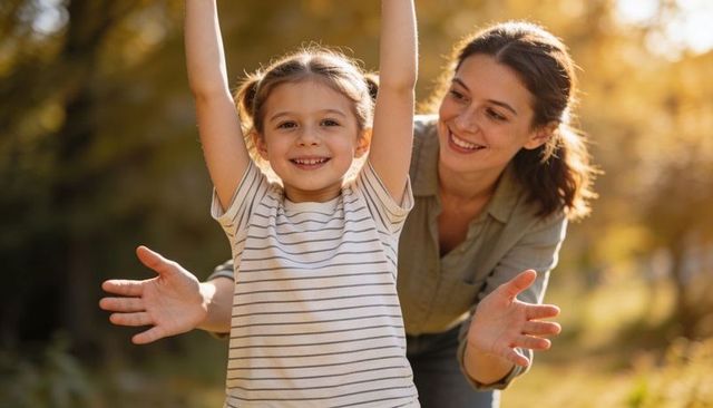 Smiling daughter reaching up while mother guiding under golden backlit autumn trees