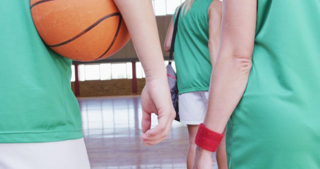 Basketball players wearing green uniforms entering the court. Ideal for sports advertisements, team-building posters, sportswear promotions, and articles related to basketball training or teamwork.