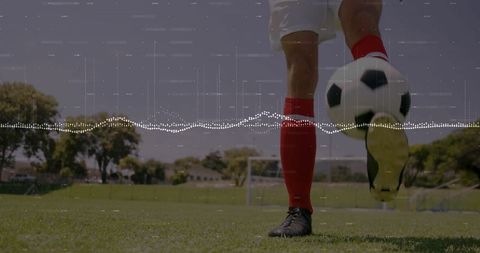 Soccer Player Kicking Ball on Field with Goalpost and Red Socks